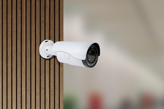 Image of a white CCTV camera mounted on a wooden wall.